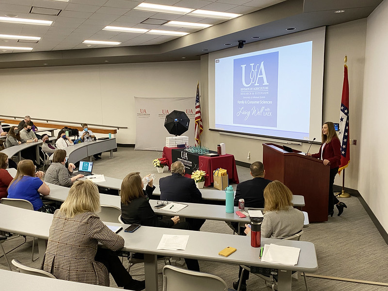 Laura Hendrix stands at a podium and addresses Cooperative Extension Service employees