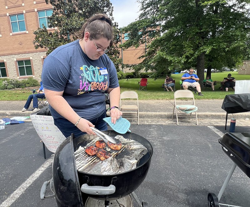 Madilyn-Odell Girl grilling chicken thighs on charcoal grill