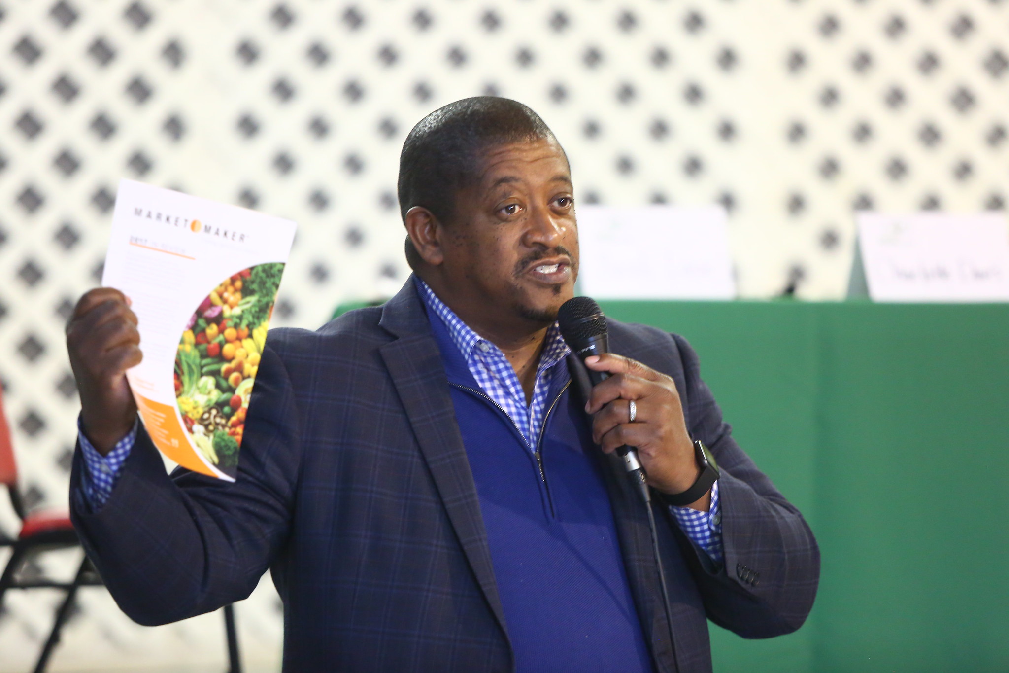 Man holding up a brochure while speaking to a group. 