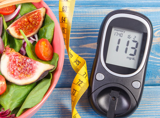 diabetes glucose meter with a pretty fresh fig salad and tape measure on a blue wooden table