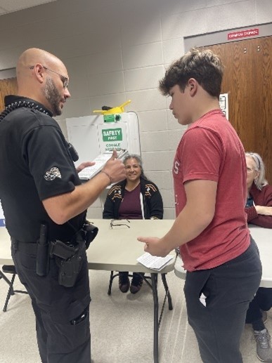 Picture of a student talking and recieving a ticket from a resource officer