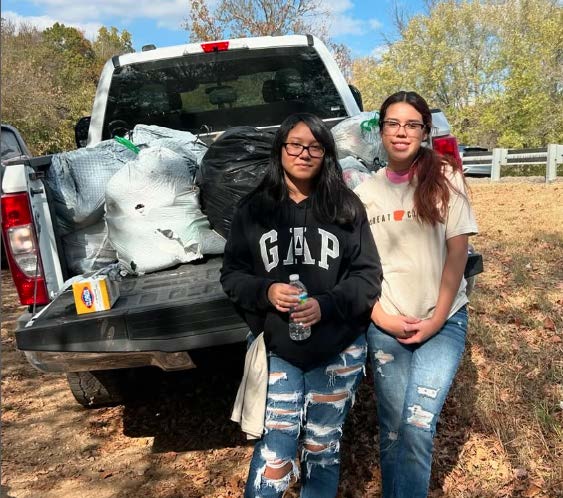 Two girls pose at a creek cleanup