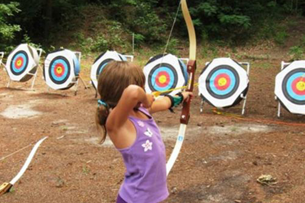 little girl shooting arrow at target